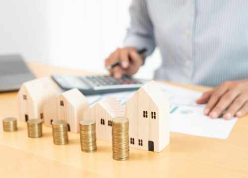 Un homme faisant des calculs sur une table où il y a des maquettes de maison