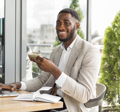 un entrepreneur boit son thé à côté de son ordinateur portable