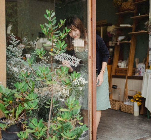 Fleuriste souriante devant sa boutique, exemple de commerce de proximité