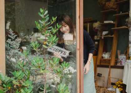 Fleuriste souriante devant sa boutique, exemple de commerce de proximité