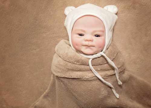 Ce bébé reborn porte un bonnet ourson.