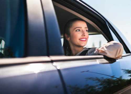 femme joyeuse dans un taxi sortant le coude de la fenêtre 
