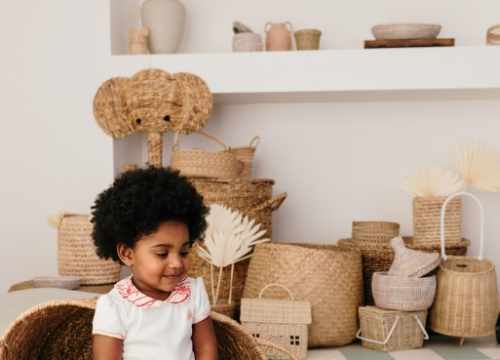 Deux bébés portant des tenues Bobo Bassari : l'un assis avec le body bébé col imprimé Bandia, l'autre allongé dans un panier en rotin, entouré d'une ambiance chaleureuse et naturelle